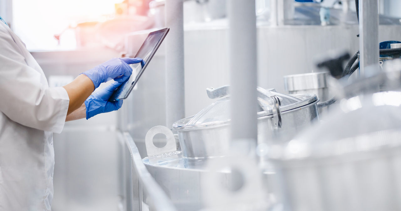 Concept food industry banner. Factory worker inspecting production line tanker in of dairy factory with computer tablet.